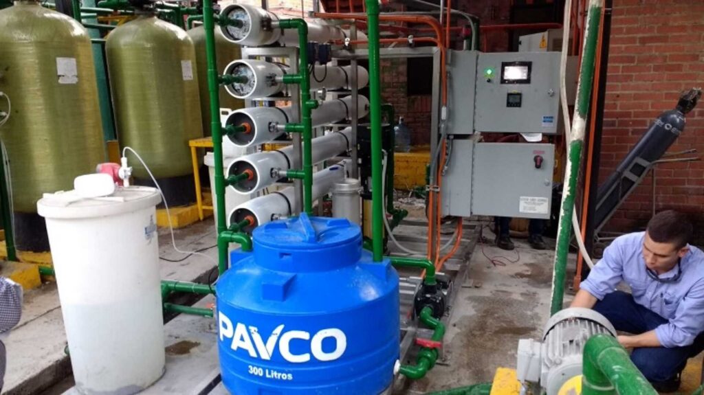 Equipo de ósmosis inversa repotenciado en planta de alimentos: tanques de filtración, portamembranas, tablero de control y un técnico ajustando la bomba.